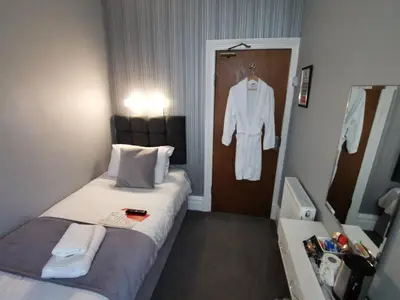 a hotel room with a bed and a robe hanging on a door at THE QUORN HOTEL in Blackpool