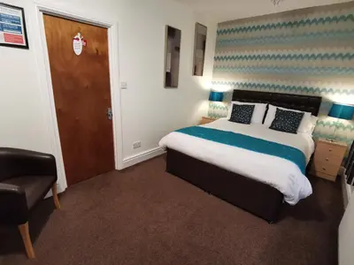 a bedroom with a bed and a chair and a door at THE QUORN HOTEL in Blackpool