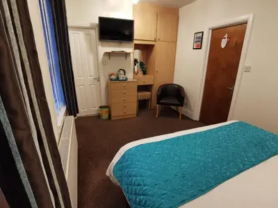 a room with a bed and a desk with a chair at THE QUORN HOTEL in Blackpool