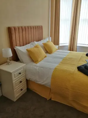 a bedroom with a bed with yellow sheets and a nightstand at THE QUORN HOTEL in Blackpool