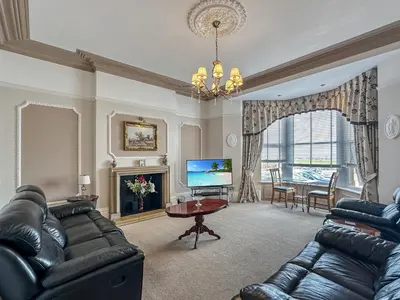 a living room with black leather furniture and a television at Granada Apartments Burbage in Blackpool