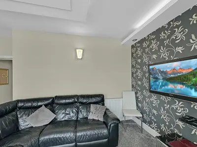 a living room with a black leather couch and a painting at Granada Apartments Burbage in Blackpool