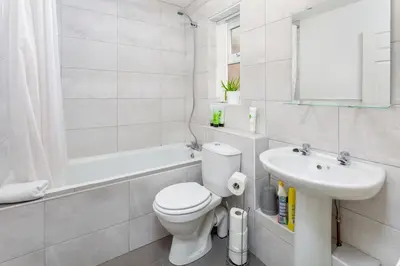 a white bathroom with a toilet and a sink at The World Famous Henderson House in Liverpool