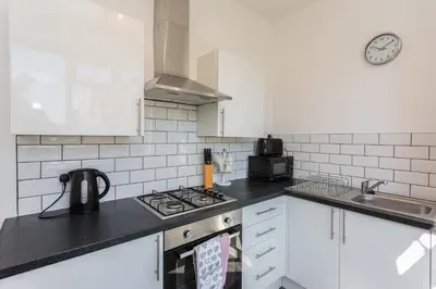 a kitchen with white cabinets and a stove top oven at Cherry Property - Mulberry Suite in Blackpool