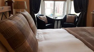 a bed in a hotel room with two chairs at The Ambassador Townhouse in Southport