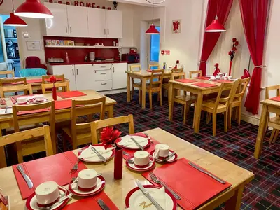 a dining room with wooden tables and a kitchen at Beeches Hotel in Blackpool