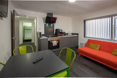 a living room with a red couch and a table at ApartHotel421 by Seafront Collection in Blackpool