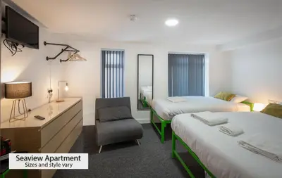 a hotel room with two beds and a chair at ApartHotel421 by Seafront Collection in Blackpool