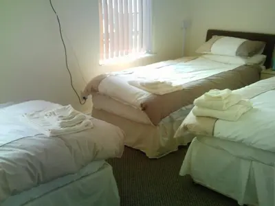a room with three beds with white sheets and a window at Arlingtons in Blackpool