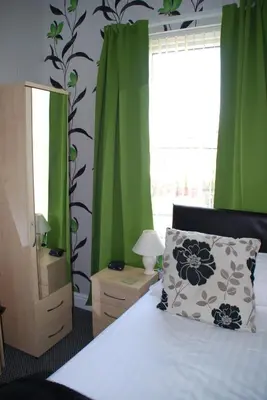 a bedroom with green curtains and a bed with a pillow at Brincliffe Hotel in Blackpool