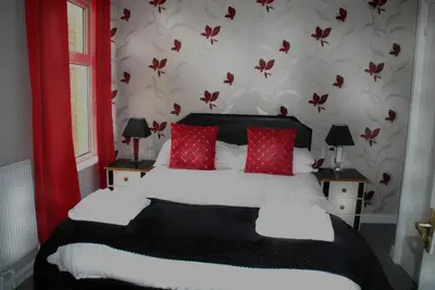a bedroom with a large bed with red pillows at Brincliffe Hotel in Blackpool