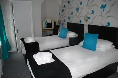 a hotel room with two beds with blue pillows at Brincliffe Hotel in Blackpool