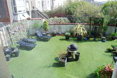 a garden with chairs and potted plants and a fence at Brincliffe Hotel in Blackpool