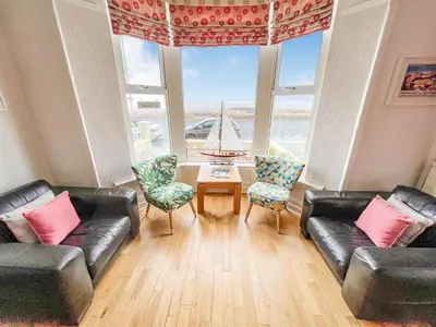 a living room with two leather couches and a table and a sailboat in at The Ashley in Morecambe