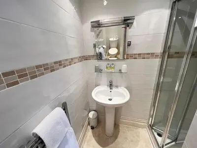 a small bathroom with a sink and a shower at The Ashley in Morecambe