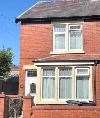 a red brick house with white windows and a gate at Entire holiday home in Blackpool with free parking and a private patio garden in Blackpool