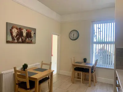 a dining room with a table and a clock on the wall at Be My Guest Liverpool in Liverpool
