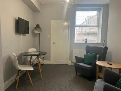 a living room with a table and chairs and a tv at Sheil Road Studios - Be My Guest Liverpool in Liverpool
