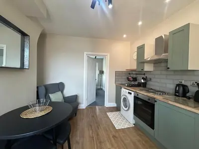 a small kitchen with a table and a washer at Sheil Road Studios - Be My Guest Liverpool in Liverpool