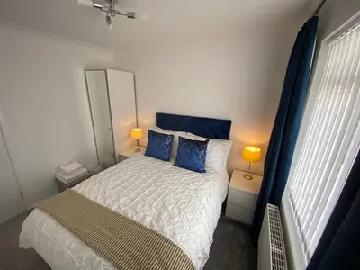 a bedroom with a king sized bed with blue pillows at COLERIDGE LODGE in Thornton