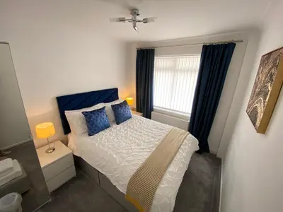 a bedroom with a bed with blue pillows and a window at COLERIDGE LODGE in Thornton