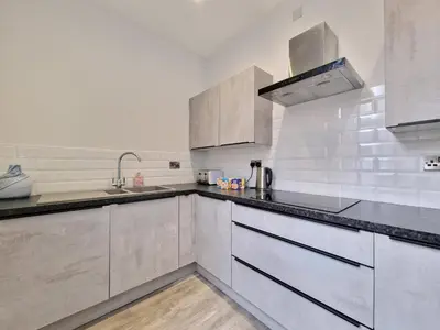a kitchen with white cabinets and black counter tops at DYSA Waterloo Apartments in Blackpool