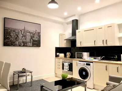 a kitchen with white cabinets and a washer at BELMONT Apartments in Liverpool