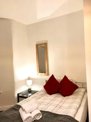 a bedroom with a bed with red pillows and a mirror at BELMONT Apartments in Liverpool