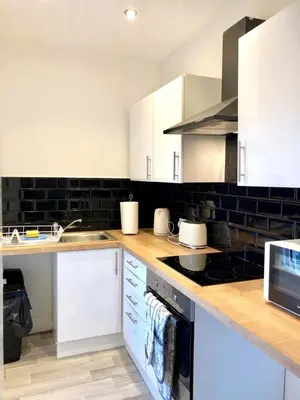 a kitchen with white cabinets and wooden counter tops at BELMONT Apartments in Liverpool