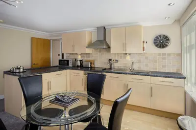 a kitchen with a glass table in a kitchen at Granada Apartments Queens Mansions in Blackpool