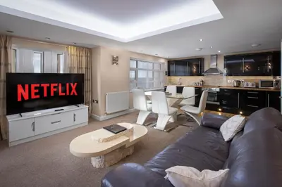 a living room with a couch and a kitchen at Granada Apartments Queens Mansions in Blackpool