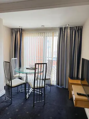 a dining room with a table and chairs and a window at Granada Apartments Queens Mansions in Blackpool