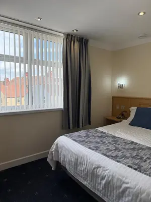 a bedroom with a bed and a large window at Granada Apartments Queens Mansions in Blackpool
