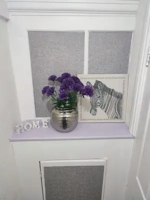 a vase with purple flowers sitting on a shelf at A home away from home now with Netflix and PS4 in Blackpool