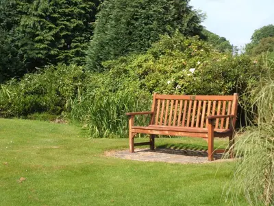a wooden bench sitting in the grass in a garden at Green Bank Farmhouse in Lancaster