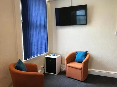 a room with two chairs and a flat screen tv at Belmont Hotel in Blackpool