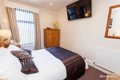 a bedroom with a white bed and a mirror at Belmont Hotel in Blackpool
