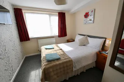a bedroom with a bed and a window with red curtains at The Tudor in Blackpool