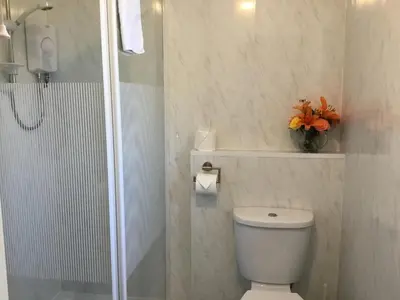 a white bathroom with a toilet and a shower at The Tudor in Blackpool