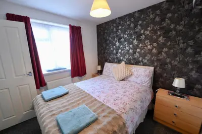a bedroom with a bed with a floral wallpaper at The Tudor in Blackpool