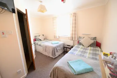 a small room with two beds and a window at The Tudor in Blackpool