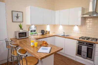 a kitchen with white cabinets and a wooden counter top at Sapphire House By Sasco in Blackpool