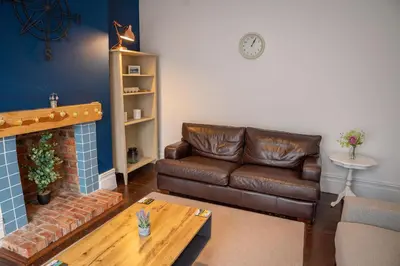 a living room with a leather couch and a fireplace at Sapphire House By Sasco in Blackpool