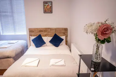 a bedroom with a bed with blue pillows and a vase of flowers at Sapphire House By Sasco in Blackpool