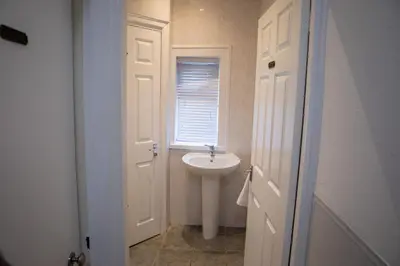 a white bathroom with a sink and a window at Sapphire House By Sasco in Blackpool