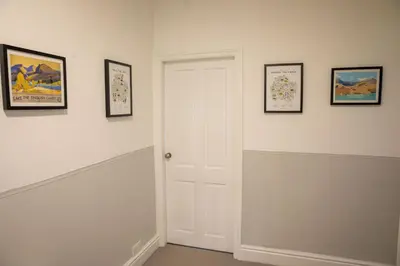 a hallway with a white door and framed pictures at Sapphire House By Sasco in Blackpool
