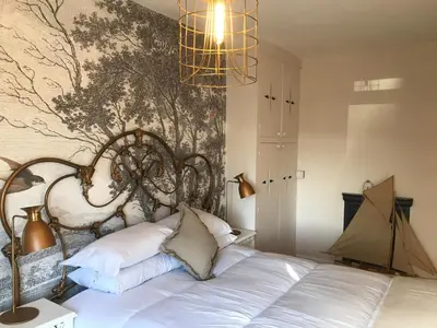 a bedroom with a white bed with a wall mural at Inglenook Cottage in Grange Over Sands