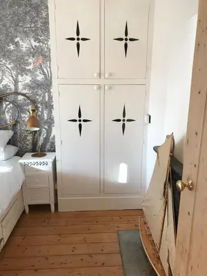 a bedroom with a white cabinet with black stars on it at Inglenook Cottage in Grange Over Sands