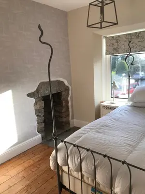 a bedroom with a bed and a stone fireplace at Inglenook Cottage in Grange Over Sands
