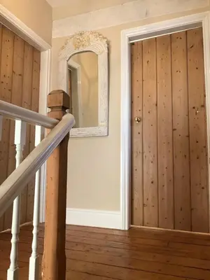 a hallway with wooden doors and a mirror at Inglenook Cottage in Grange Over Sands